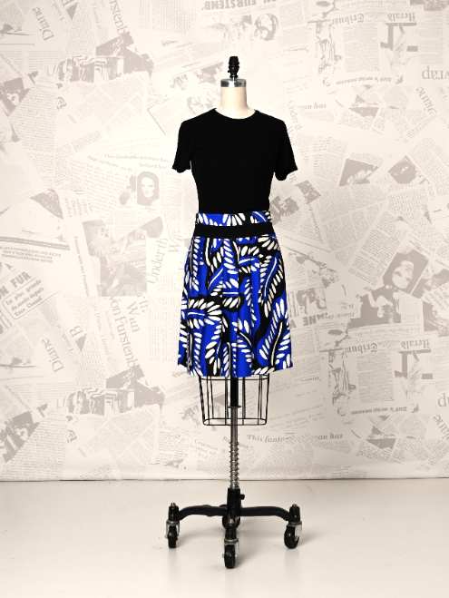 Mannequin wearing a black t-shirt and blue patterned skirt against a newspaper background