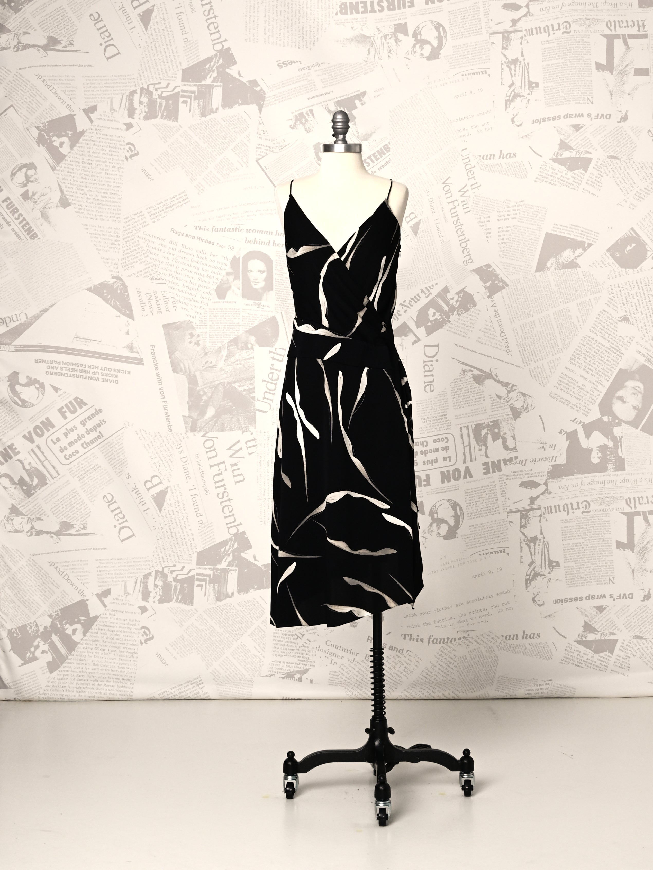 Black and white patterned dress on a mannequin against a newspaper-patterned wall.