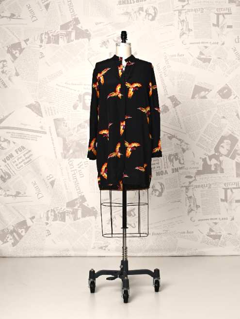 Black dress with orange patterns on a mannequin against a newspaper background