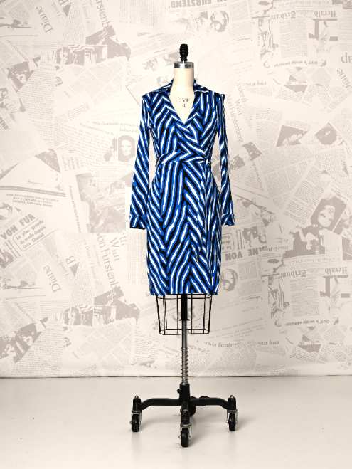 Blue and white striped dress on a mannequin against a newspaper-patterned wall.